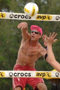 man spiking a volleyball over the net